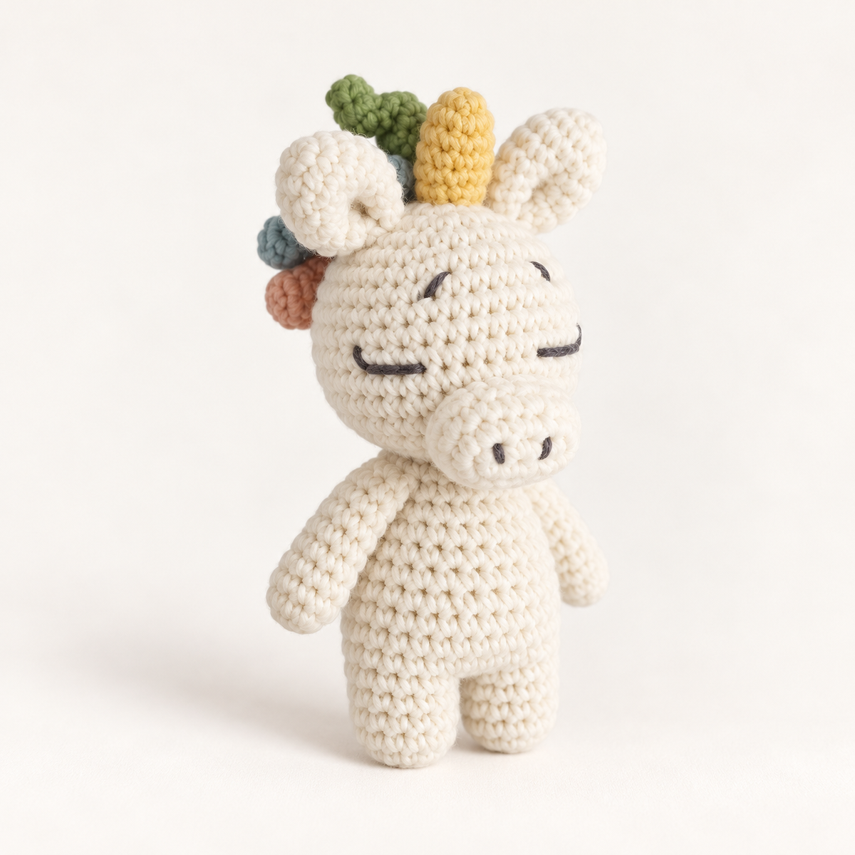 Cream hand-crocheted unicorn toy with a colourful pastel mane
