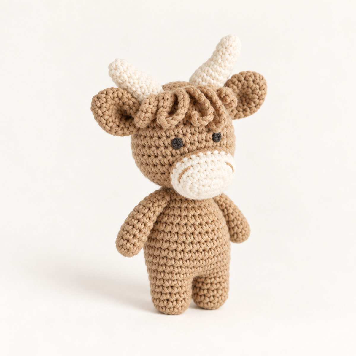 Brown hand-crocheted cow toy with cream-coloured muzzle and horns