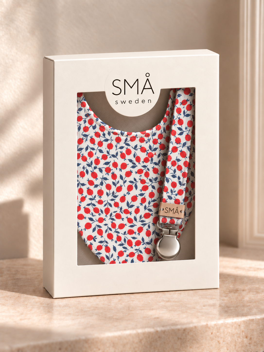 SMÅ Liberty baby bib and matching pacifier clip in red berry and navy floral print, presented in a white gift box