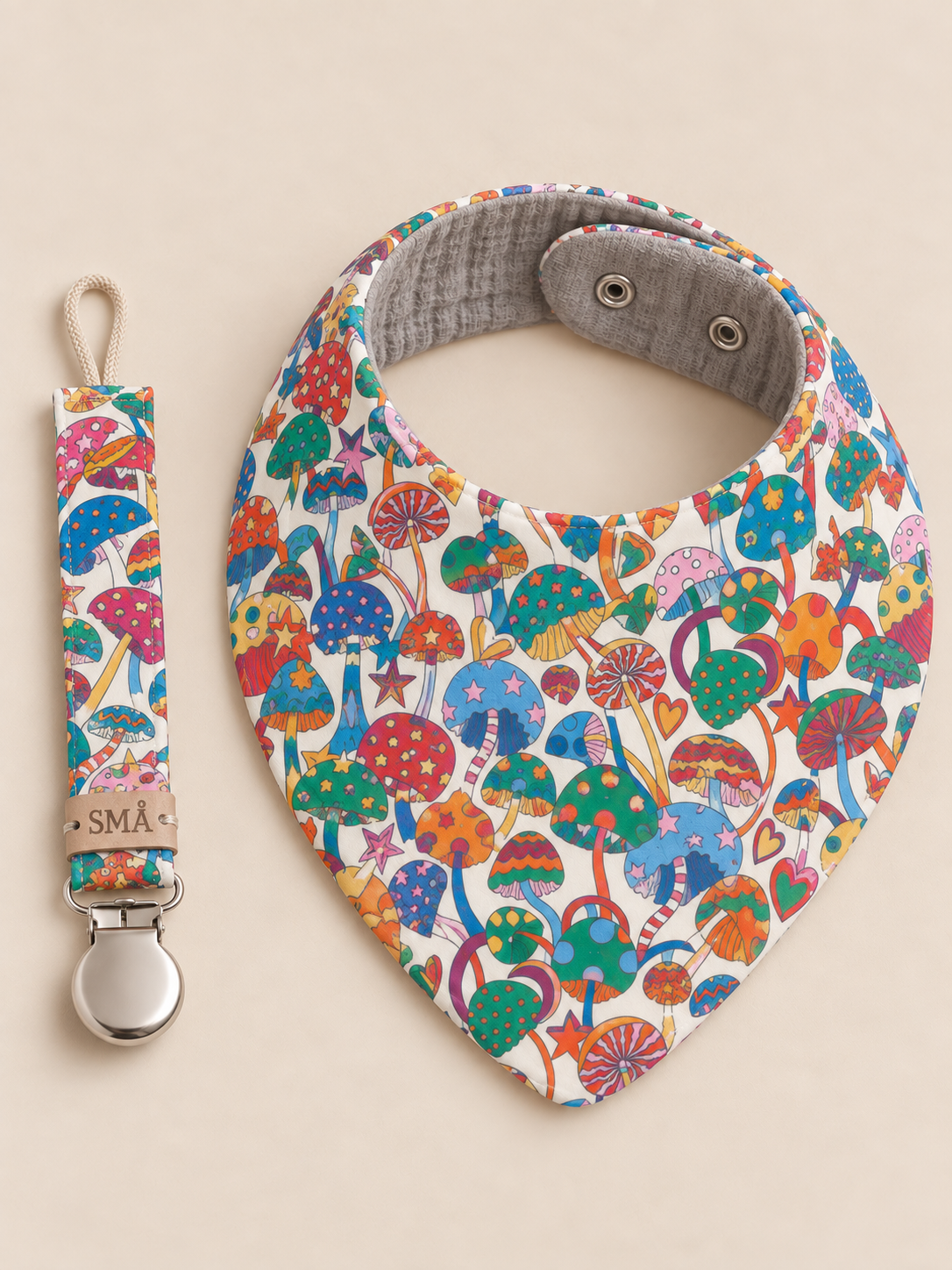 Liberty Magic baby bib and matching pacifier clip displayed together on a warm ivory background