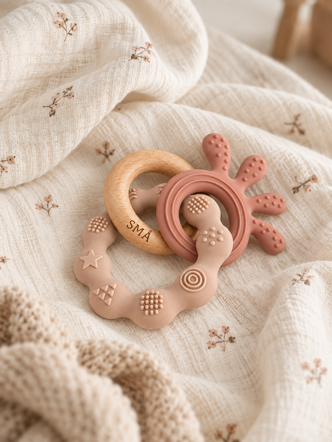 SMÅ Octopus Baby Teether in natural beech wood and pink silicone on floral muslin fabric