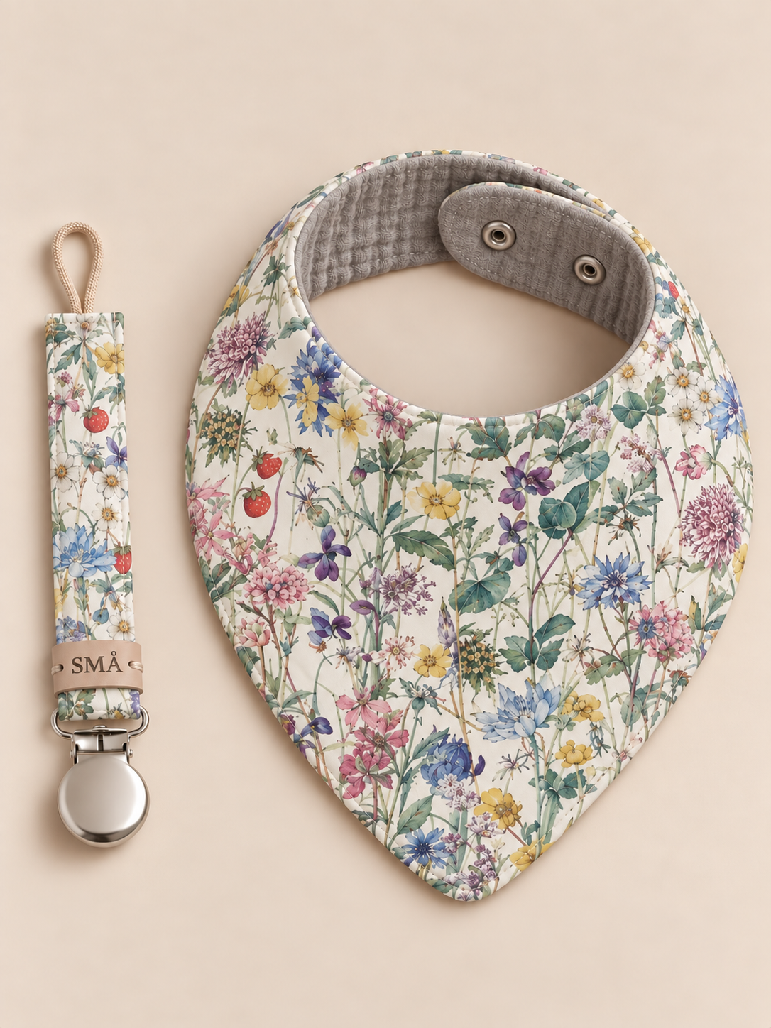 SMÅ Wild Flowers Liberty baby bib and matching pacifier clip on ivory background